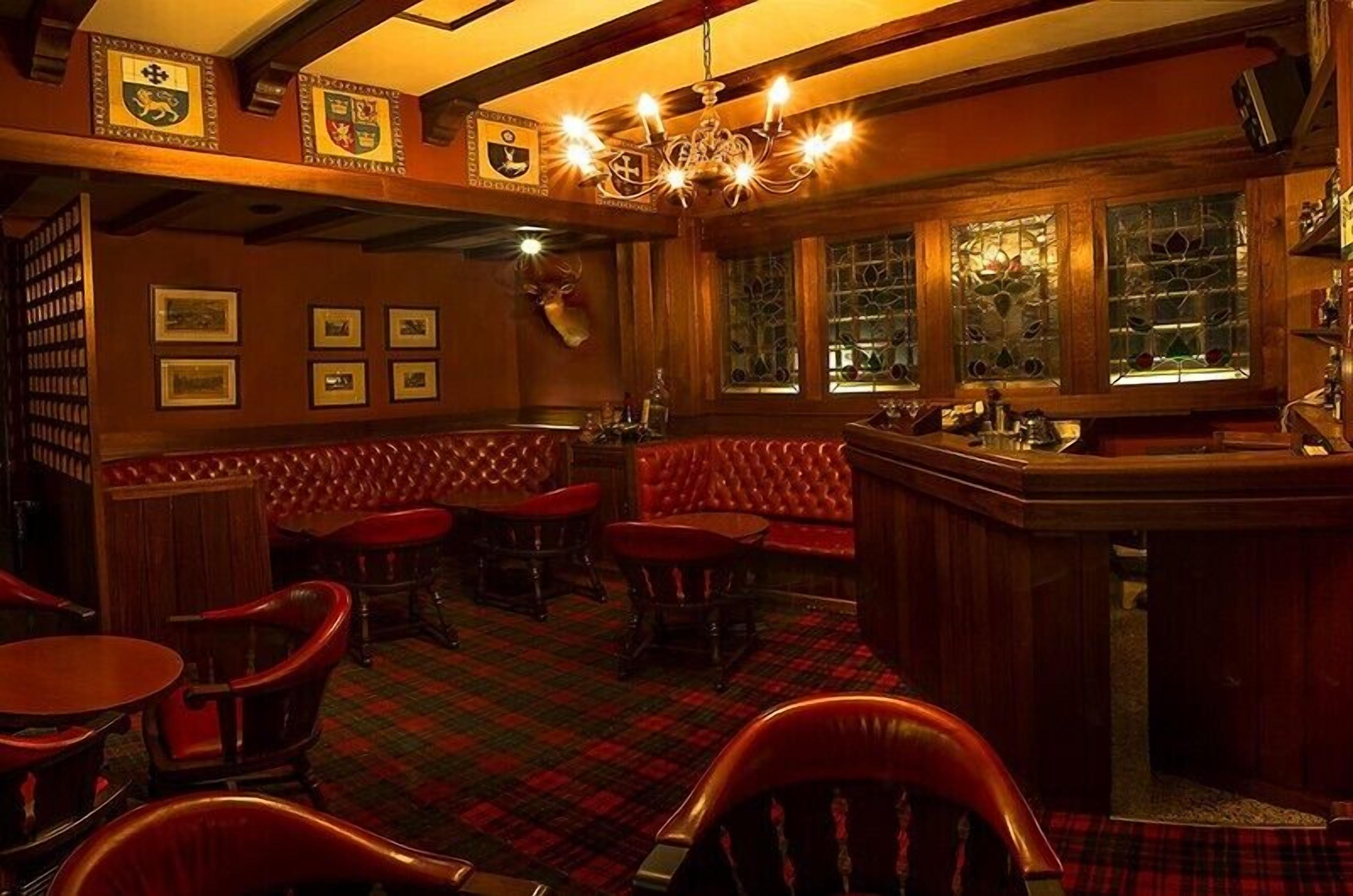 A bar area with red leather booths, wooden bar counter, and framed pictures on the wall.