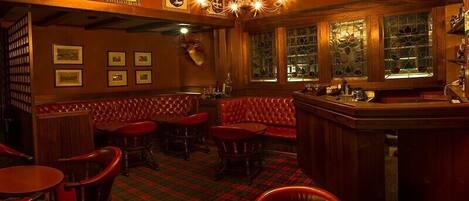 A bar area with red leather booths, wooden bar counter, and framed pictures on the wall.