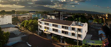 A multi-story building with a flat roof, surrounded by trees and other buildings.