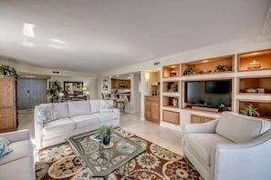 A spacious living area with a sofa, coffee table, TV, and built-in shelving.