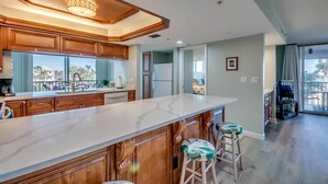 Una cocina moderna con armarios de madera, encimera de mármol y taburetes de bar.