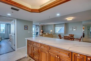 A kitchen with a large island, wooden cabinets, and a dining area with chairs and a table.
