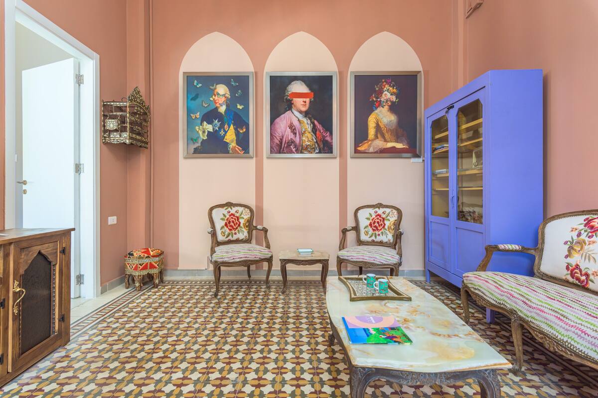 A room with a patterned floor, two armchairs, a sofa, a coffee table, and a cabinet.