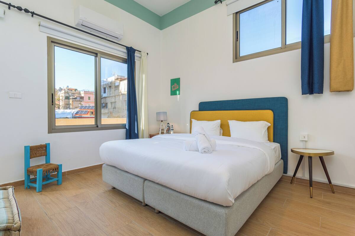 A neatly arranged hotel room with a large bed, a small table, and a chair.