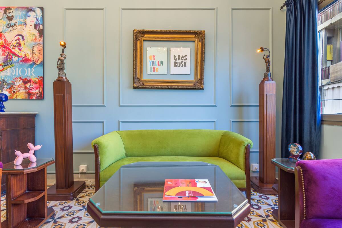 A living room with a green sofa, a glass coffee table, and a framed picture on the wall.