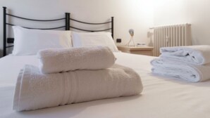 A neatly made bed with white linens and two folded towels on the bed. - Italianway Easy - Tadino 13 B (Milan)