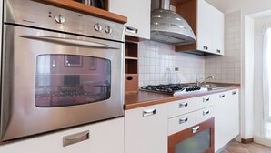 A modern kitchen with stainless steel appliances, wooden cabinets, and a tiled backsplash. - Italianway Easy - Tadino 13 B (Milan)