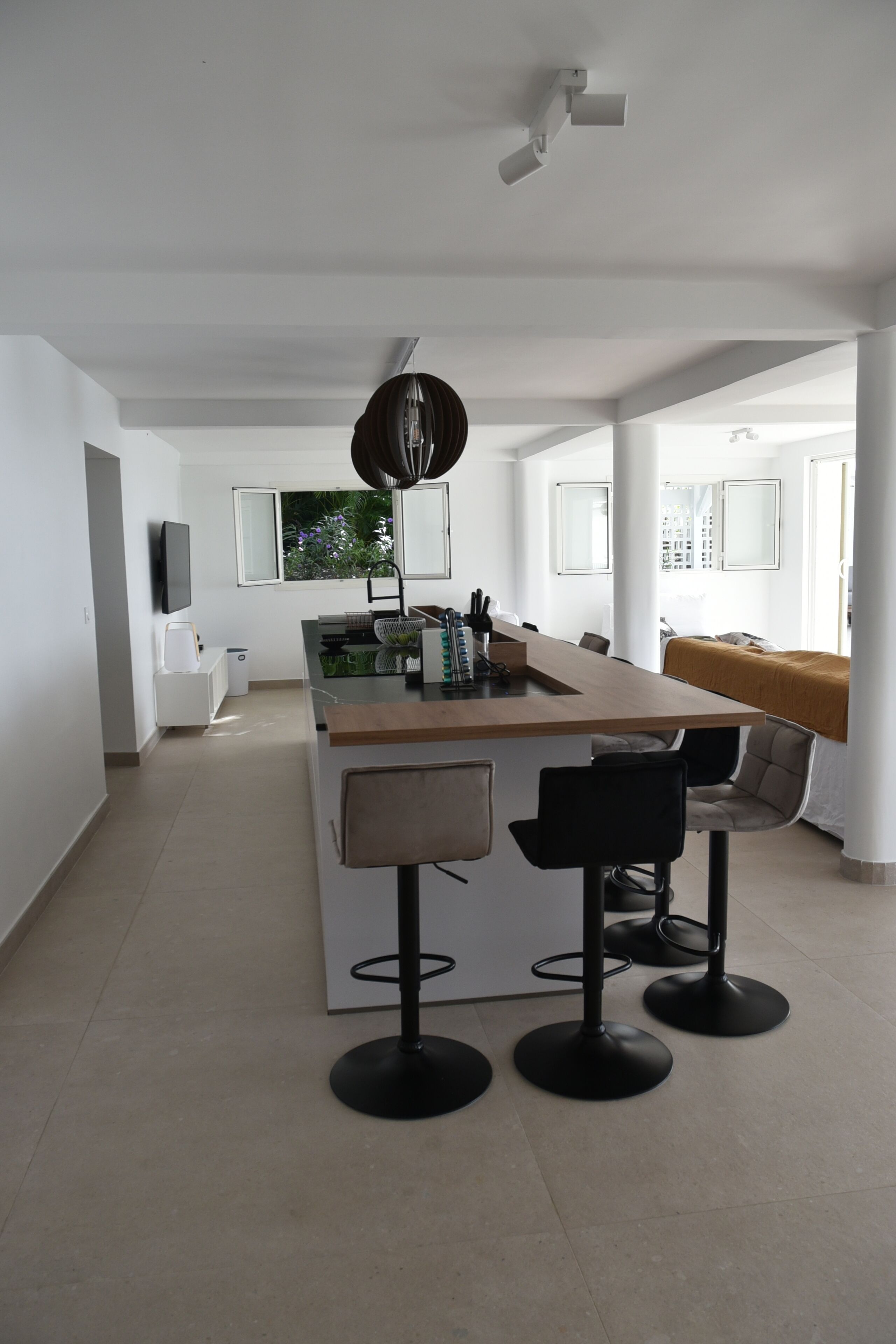 Una cocina moderna con una isla central, taburetes de bar y un ventanal grande.