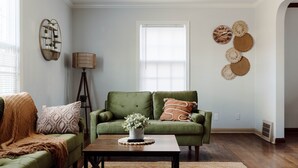 Un salon avec un canapé vert, une table basse en bois ornée d’une plante et une lampe.