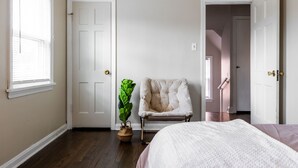 Une chambre avec une grande fenêtre, une chaise, une plante et un lit.