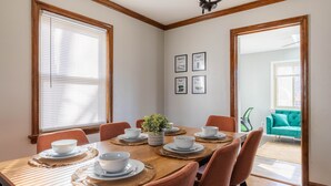 Une salle à manger avec une table en bois dressée pour six personnes, entourée de chaises orange.