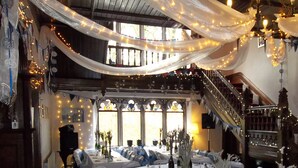 A banquet hall with round tables, white tablecloths, and blue chair covers.