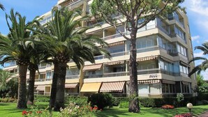 A multi-story hotel with balconies, surrounded by palm trees and well-maintained gardens. - Renovated Apartment With Terrace Facing THE SEA (Cannes)