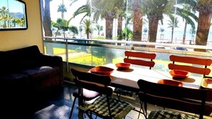A balcony with a table and chairs, overlooking a palm tree-lined beach. - Renovated Apartment With Terrace Facing THE SEA (Cannes)