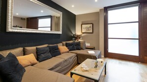 Ein modernes Wohnzimmer mit einem großen Spiegel, einem Sofa, einem Couchtisch und einer Glastür, die auf einen Balkon führt.