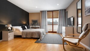Ein modernes Schlafzimmer mit Bett, Nachttisch, Sessel und einem großen Fenster mit Vorhängen.