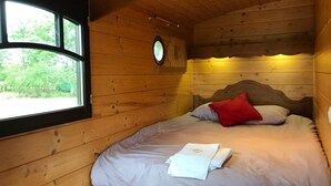 Una habitación de cabaña de madera con una cama, un ventanal y un reloj en la pared.