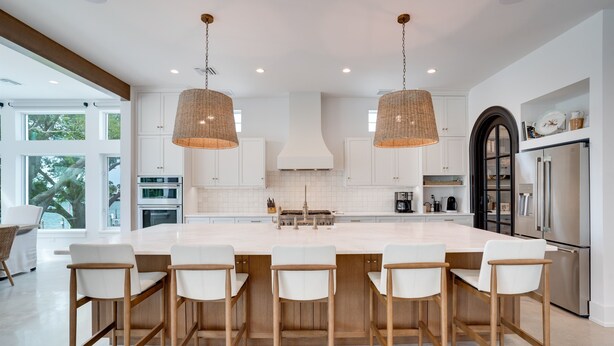 A modern kitchen with a large island, white cabinetry, stainless steel appliances, and a large window providing natural light. - New House, Waterfront, Pool, Hot Tub, Golf Cart (Indian Rocks Beach)