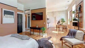 Moderni hotellihuone, jossa on sänky, työpöytä, ruokailutila ja oleskelualue.