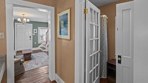 A hallway with a wooden floor, a white door, and a framed picture on the wall. - Historic District: Downtown New Bern (New Bern)