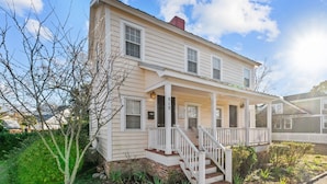 A two-story house with a porch, a small garden, and a brick foundation. - Historic District: Downtown New Bern (New Bern)