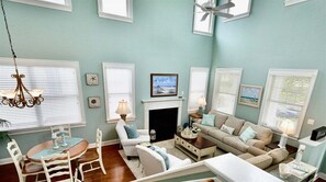 Un salon avec une cheminée, une table à manger avec des chaises, un canapé et un ventilateur de plafond.