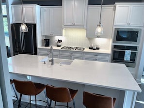 Una cocina moderna con armarios blancos, una isla central con un fregadero y una estufa.