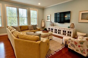 A living room with a sofa, a patterned armchair, a TV, and a cabinet.