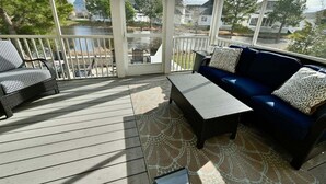A covered outdoor deck with a sofa, chairs, and a table. - Bayside Resort 5BR, 4 Full Baths 2 Suite Luxury Ho (Selbyville)