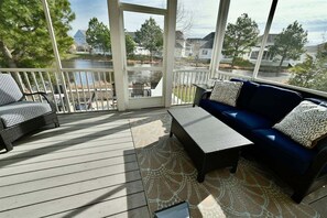 A covered outdoor deck with a sofa, chairs, and a table.