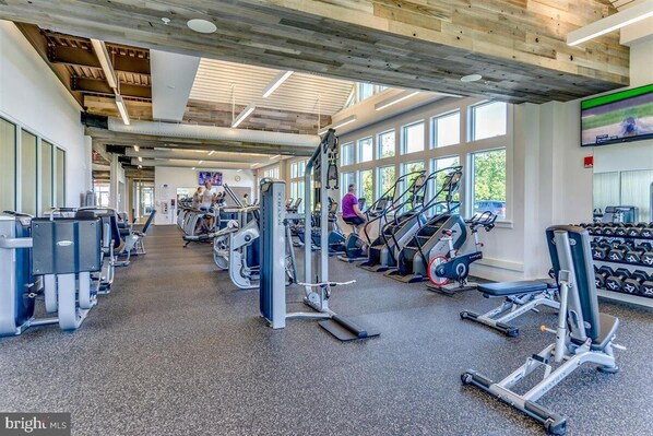 Ein Fitnessraum mit Cardiogeräten, Kraftstationen und Kurzhanteln.