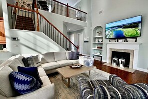 A living room with a sofa, a coffee table, a fireplace, a TV, and a staircase.