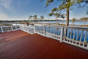 A wooden deck with white railings overlooking a body of water and trees.