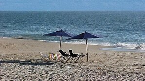 A beach with two umbrellas and beach chairs. - Bethany Beach Waterfront House w Stunning Views * (Bethany Beach)
