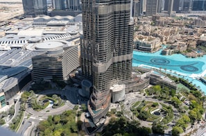 A high-rise building with a unique circular design, surrounded by a landscaped area with palm trees and a pool.