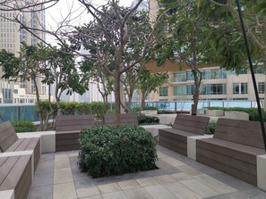An outdoor seating area with benches and a central planter. - Vacay Lettings - Burj Vista Tower 1 (Dubai)
