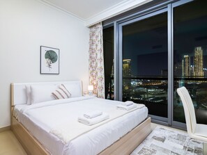 A modern hotel room with a large bed, a city view, and a framed artwork on the wall. - Vacay Lettings - Burj Vista Tower 1 (Dubai)