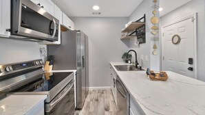 Una cocina moderna con electrodomésticos de acero inoxidable, encimera de mármol y horno empotrado.