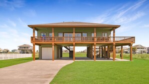 Une maison à deux étages avec un balcon, un garage et une pelouse bien entretenue.
