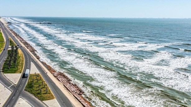 A coastal road with a bridge over the ocean, a beach, and a highway. - Coastal Paradise | 2 Bedrooms | Pool | by Rose (Galveston)