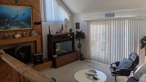 Un salon comprenant un téléviseur, une cheminée, une table à manger et un fauteuil.