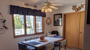 Un espace repas comprenant une table, des chaises, un ventilateur de plafond et une vue sur l’extérieur.
