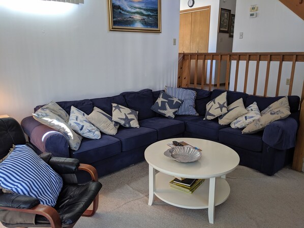 A living room with a dark blue sofa, a white coffee table, and a black leather chair. - 4 Bedroom Oceanside house in South Bethany (Bethany Beach)