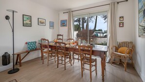 Een eethoek met een houten tafel, stoelen, een bankje en een vloerlamp.