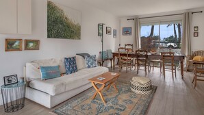 Een woonkamer met een bank, salontafel en een eetgedeelte met stoelen en een tafel.