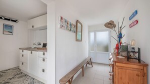 Een moderne keuken met witte kasten, een houten bank en een eethoek met een witte deur.