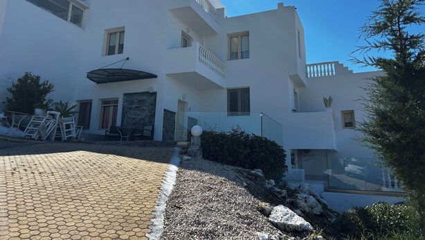 A modern multi-story building with a white exterior, a covered outdoor seating area, and a paved driveway. - Villa - Sleeps 10 - Pool - Garden - Parking (Hersonissos)