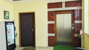 Vestíbulo de hotel con refrigerador, puerta, ascensor y un tapete verde.