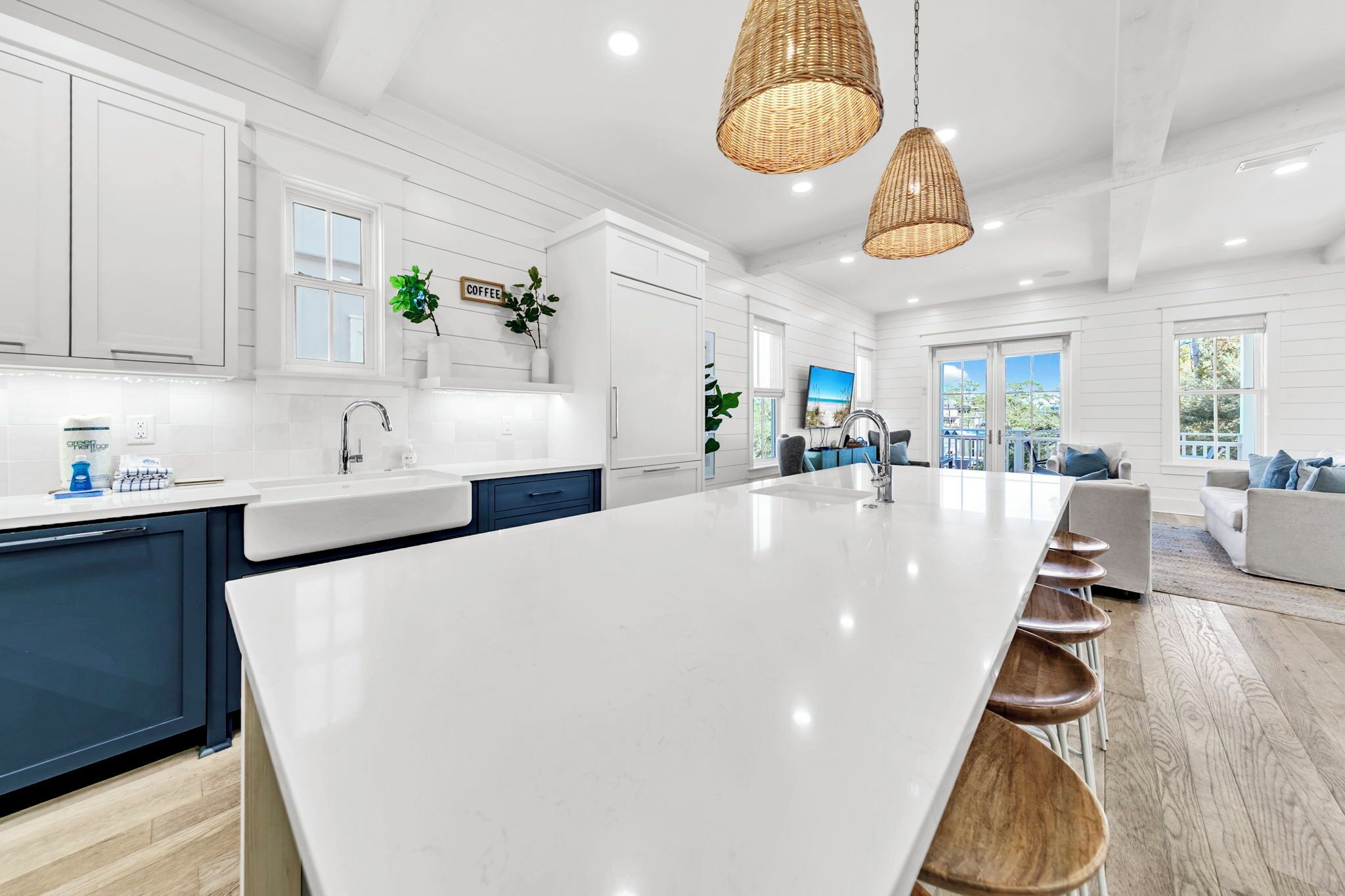A modern kitchen with a large island, white cabinetry, and a dining area with bar stools.