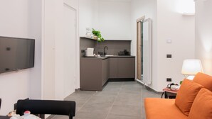 A modern living room with a sofa, a dining table with chairs, and a kitchen area in the background.